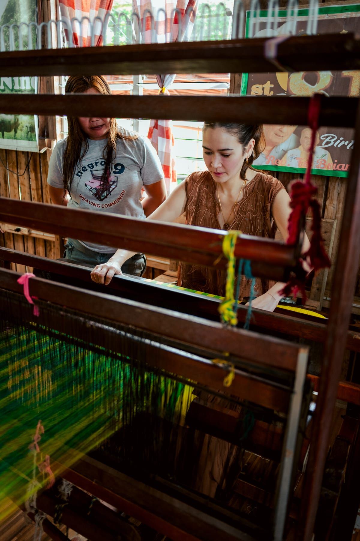 Bela Padilla at a loom as a weaver looks on