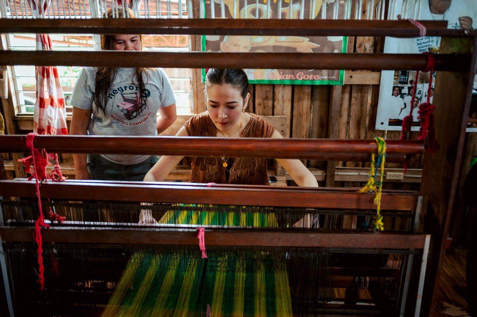 Bela Padilla at the loom with green and yellow threads
