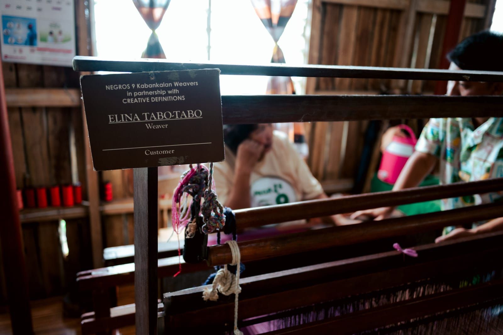 A weaver's name card at her loom