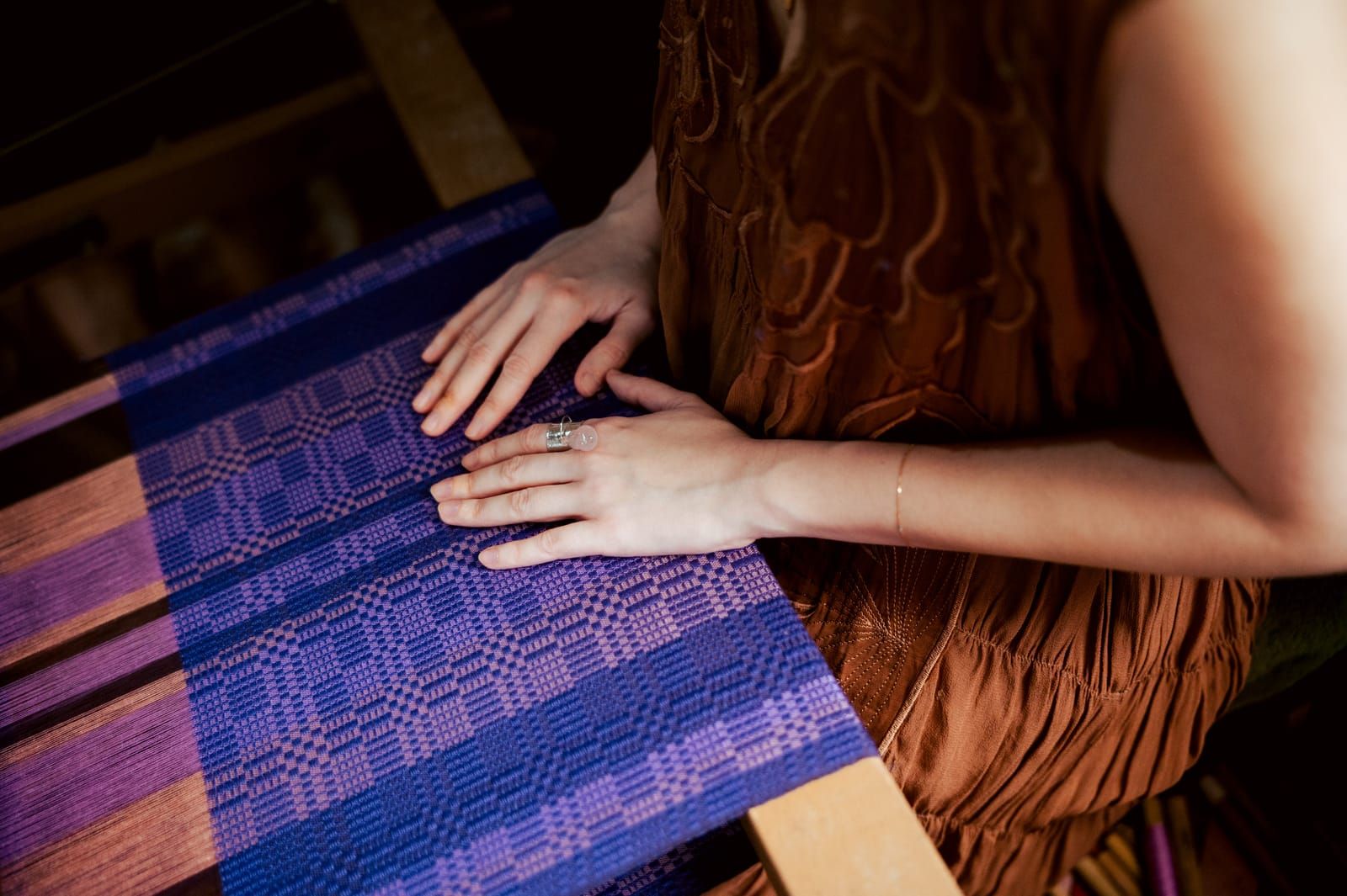 Bela Padilla's hands on purple handwoven fabric