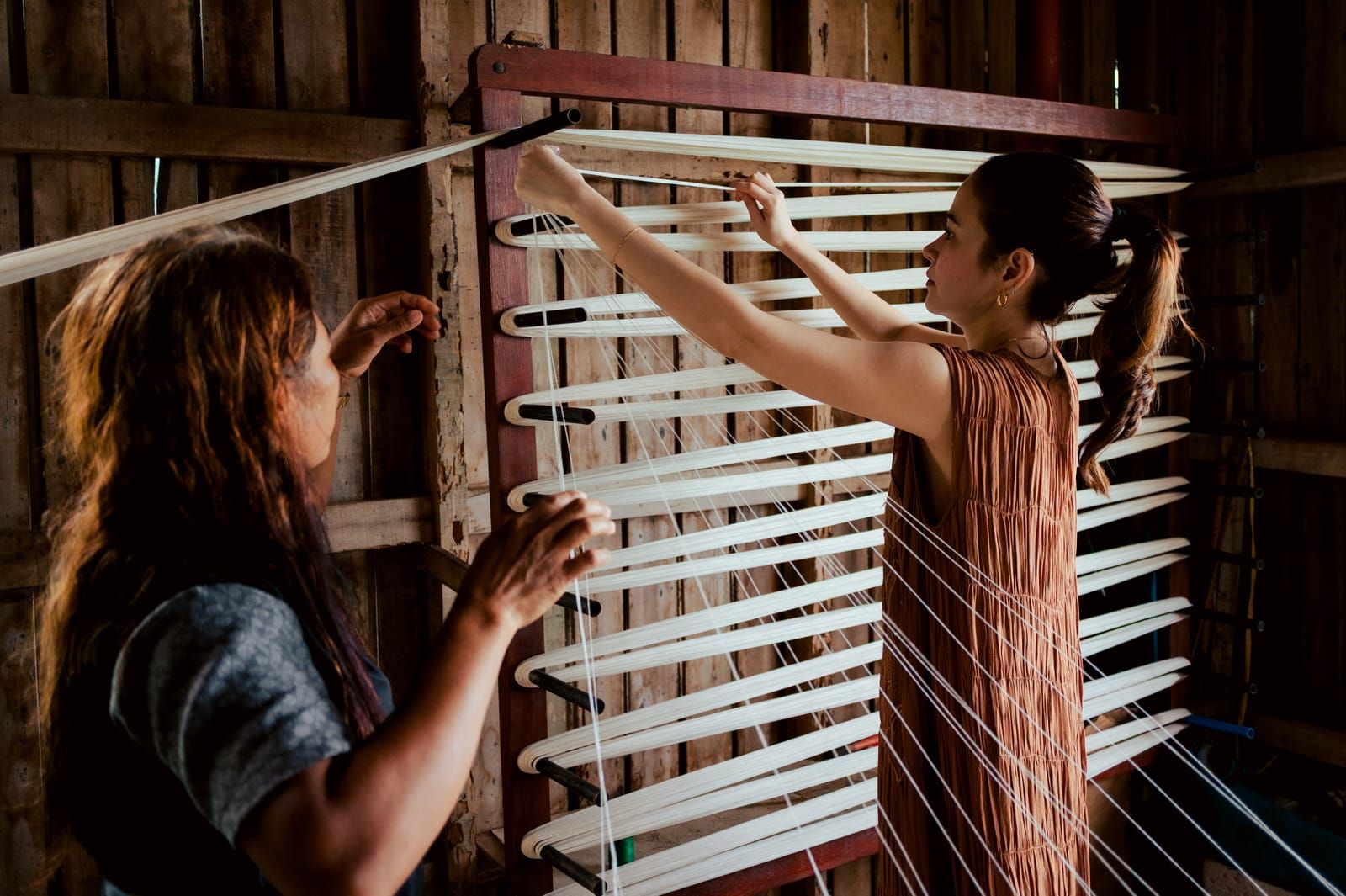 A weaver showing Bela Padilla how to warp threads