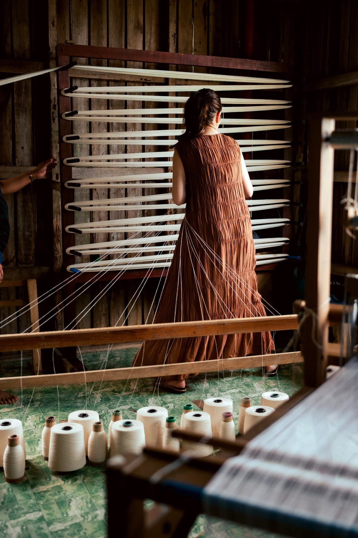 Bela Padilla at the warping frame above spools of thread