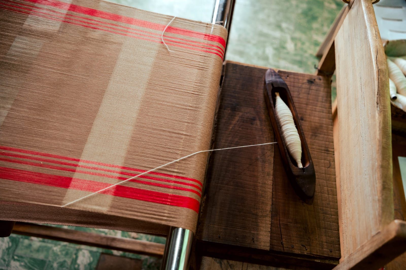 A shuttle on red and cream handwoven fabric