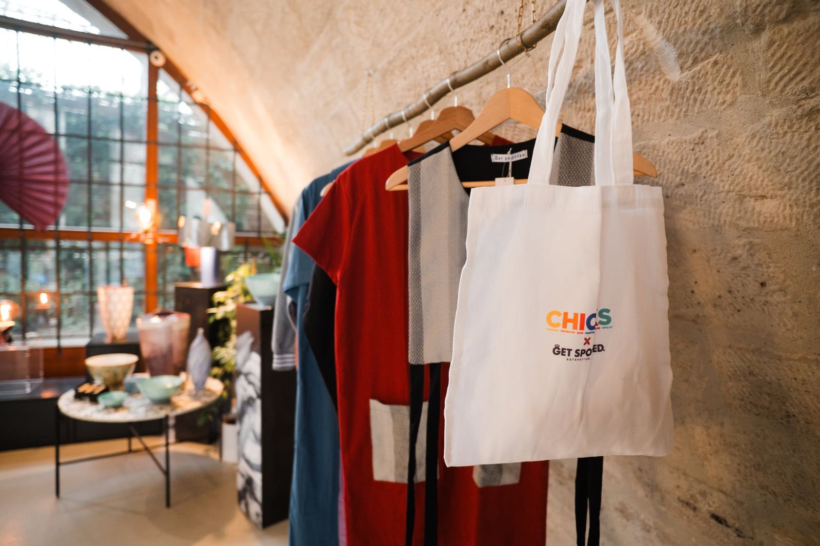 A CHICKS x Get Spotted tote bag hanging beside the collection under the stone arch