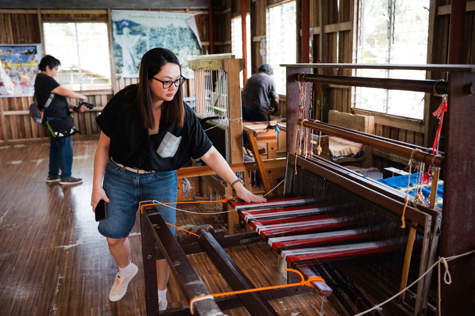 A visitor looking closely at a fabric on the loom at the weaving centre