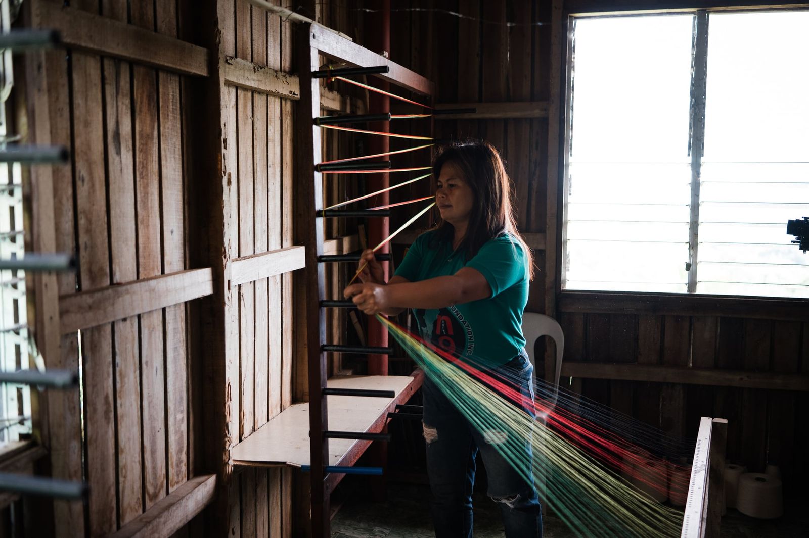 A weaver warping colourful threads on a wooden warping frame