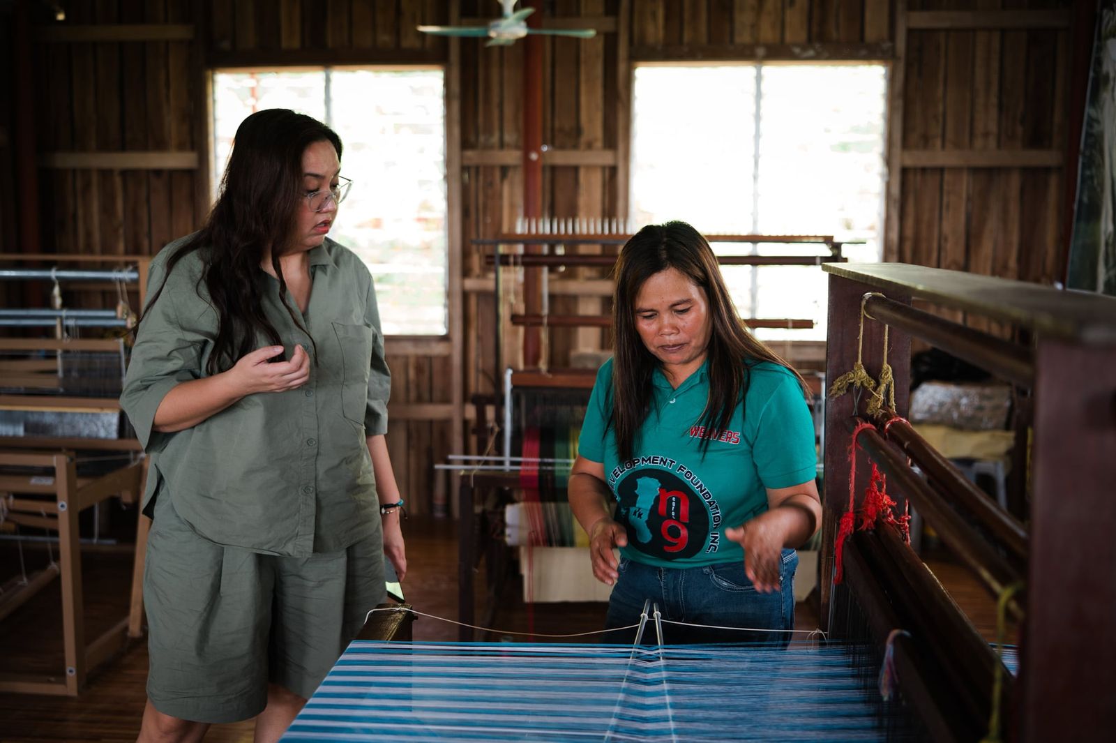 Talking with a weaver beside the loom at the weaving centre
