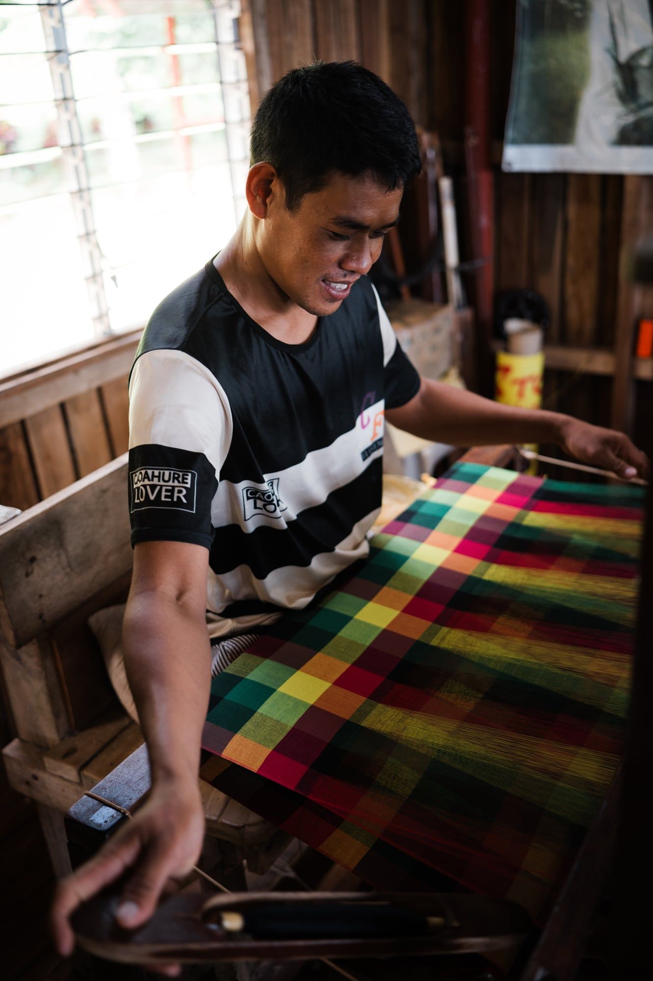 A young weaver at work on a bright plaid fabric
