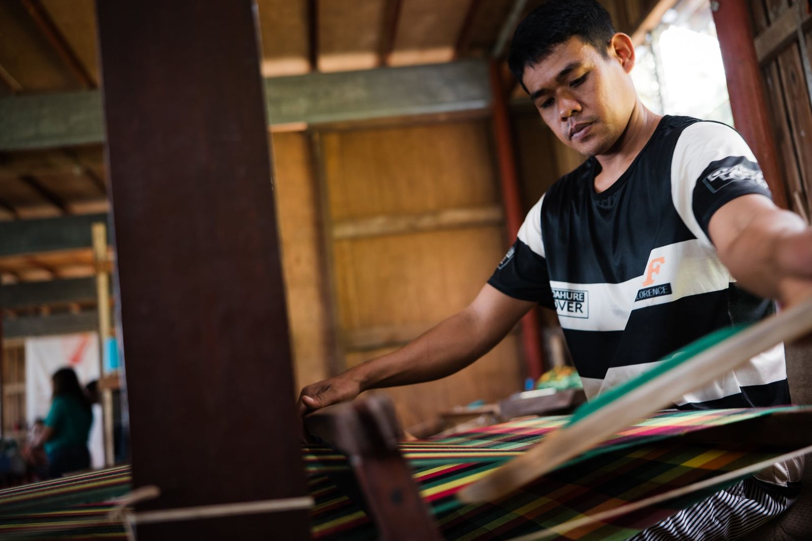 A young weaver passing the shuttle across the loom